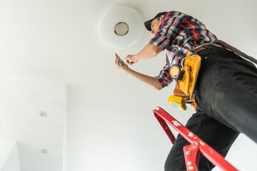 Electrician man worker installing ceiling lamp