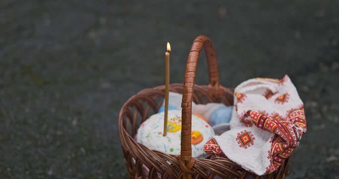 Man's hand lights candle standing in basket with Easter cake and towel. Celebration of Christian religious holiday of Easter.