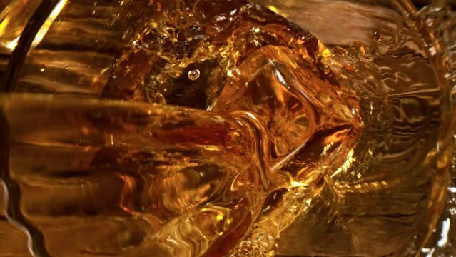 Pouring whisky into glass on old wooden table in super slow motion, camera move. Shot with high speed cinema camera, 1000fps.