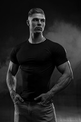 Athletic sexy man in black t-shirt and jeans posing in studio