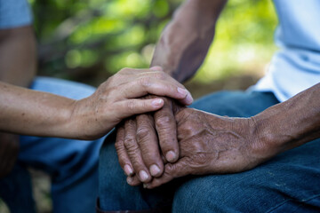 Close-up of elderly caregiver and daughter's hands.