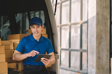 Asian delivery man in cargo van checking boxes.