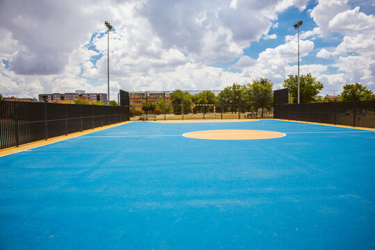 Empty outdoor basketball court and blue sky. Blue basketball court for soccer, outside in sunny summer day. A modern playground for sports without people. Playground flooring for sport activities.