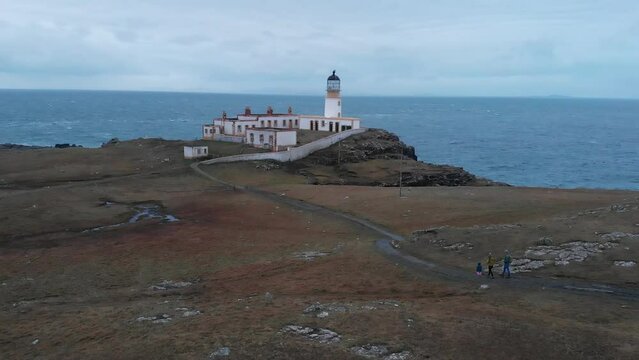 Personnes qui marche vers un phare au coucher du soleil