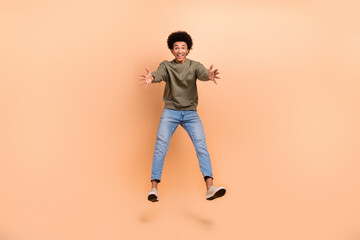 Naklejka premium Full body length cadre of overjoyed friendly person youngster guy jumping want cuddles meeting old mates isolated on beige color background