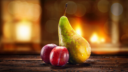 Wet pear and plums with water drops. Pear and plums on an abstract blurred background