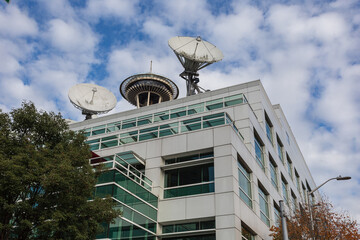 Generic office building with vintage satallites and top of space needle with cloudy sky