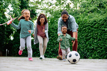 Happy African American family has fun while playing together outdoors.