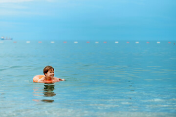 A child swims in the sea on an inflatable ring.
