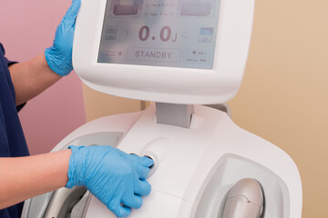 the cosmetologist includes a cosmetology device for the prevention of aging, an ultraforming device, a cosmetologist's hand in a blue glove, hardware cosmetology