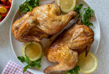Oven roast half chicken on a platter with lemon and parsley garnish