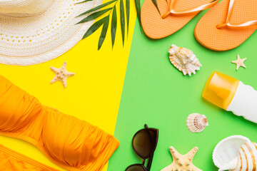 Woman swimwear and beach accessories flat lay top view on colored background Summer travel concept. bikini swimsuit, straw hat and seasheels. Copy space Top view