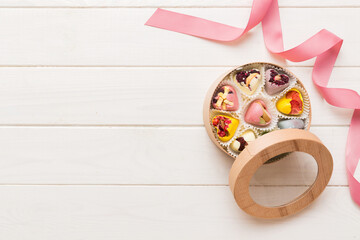 Holiday composition: sweet candy, with gift boxes with bow and chocolate hearts, photo template, background. Top View with copy space on colored background