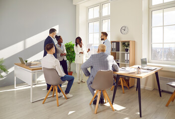 Female leader giving some ideas about project to her partners. Multiethnic business people negotiating, sharing ideas, brainstorming during meeting in office. Informal conversation