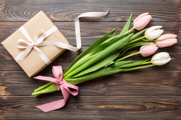 Pink tulips flowers and gift or present box on colored table background. Mothers Day, Birthday, Womens Day, celebration concept. Space for text top view