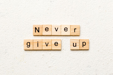 never give up word written on wood block. never give up text on cement table for your desing,...
