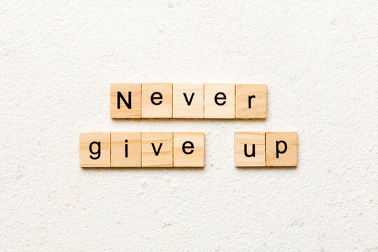 never give up word written on wood block. never give up text on cement table for your desing, concept