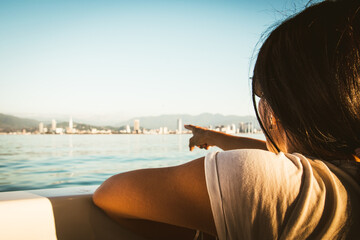 Tourist Woman sits on the boat and looks to scenic view of Batumi and landmarks during romantic...