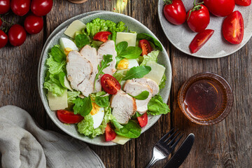 Salad of chicken fillet, eggs, tomatoes and cheese in a plate. Caesar salad