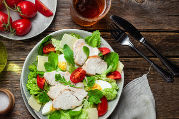 Salad of chicken fillet, eggs, tomatoes and cheese in a plate. Caesar salad