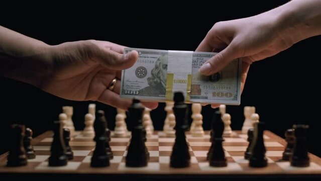 Caucasian Woman Giving Stack of Cash to Latino Man, Over Rotating Chess Board. Shot with ARRI Alexa in ArriRaw at 120 fps, exported 23.98 fps QuickTime Apple ProRes 422 HQ.