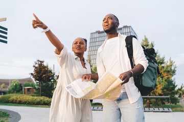 Black couple with map looking away in city