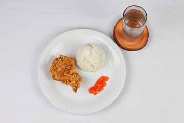 Crispy fried chicken served with rice and chilli sauce on a white plate
