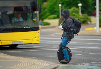 Man riding on unicycle, driving single wheel. Unrecognizable man crossing road on electric unicycle, commuting to work. Portable individual transportation vehicle. Man on electric monowheel (EUC) © Tricky Shark