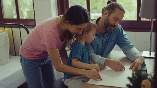 Caucasian family painting on paper with son indoors in house. Little son learn how to draw art picture enjoy creativity with mother and father in house.