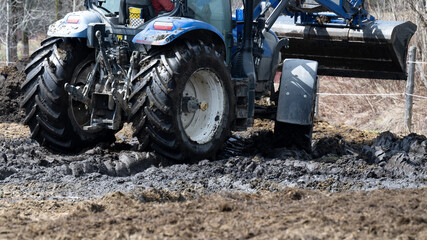 A tractor moving horse manure in a field