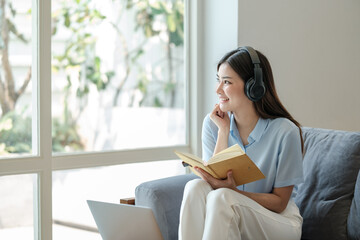 Beautiful asian woman online learning with laptop in living room.