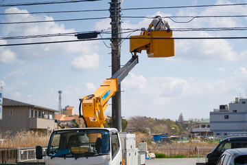 青空の下、高所作業車で電気工事