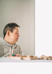 elderly Down syndrome woman at home play in tower from wooden blocks