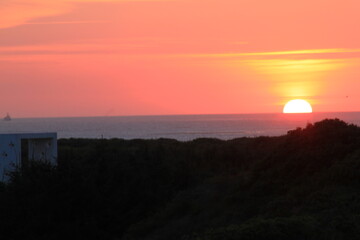 at the sea the red-golden sun shines out from behind the clouds before it sets