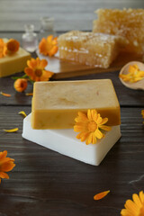 Natural handmade soap with calendula (pot marigold), oil essential and honeycomb on wooden background. Healthy skin care. SPA concept. Side view.