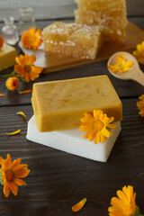 Natural handmade soap with calendula (pot marigold), oil essential and honeycomb on rustic wooden background. Healthy skin care. SPA concept. Side view.