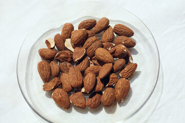 almond nuts lie on a glass plate on a white table
