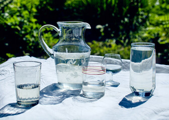 glasses and a carafe filled with water stand on a white tablecloth