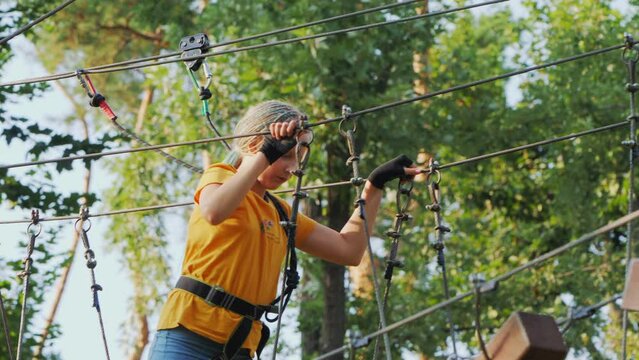 A child climbs ropes high in the trees - having fun in a rope city in an amusement park