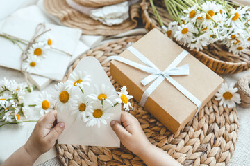 Envelope with daisies in hand and aesthetic decor, holiday concept