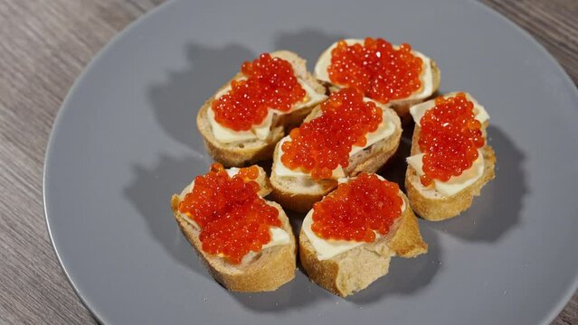 sandwiches with red caviar on a gray plate. white bread with butter and red salmon caviar