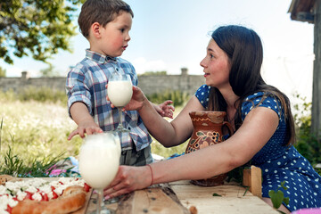 happy young woman and her son having a picnic outdoor on a summer day in countryside.