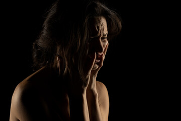 Silhouette of young unhappy crying woman on black background