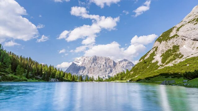 Timelapse video of a crystal clear alpine lake with a mountain range in the background. The Zugspitze, the tallest mountain in Germany, rises behind the Seebensee lake near Ehrwald in Tyrol, Austria.