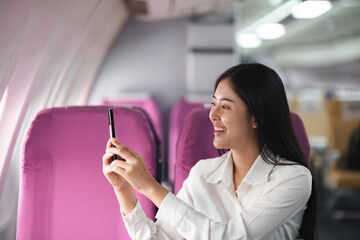 Young asian woman passenger taking photo from the window of the airplane during flight.