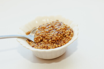 grain mustard in a white bowl on a white table.