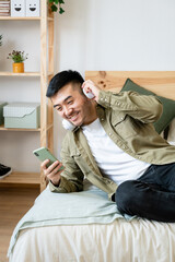 Man lying in bed watching videos on his cell phone.