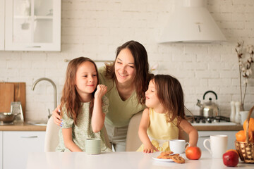 family, food and people concept - happy mother and daughters having breakfast at home