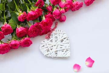 Decorative white heart made of vines, Valentine's Day on the background of a bouquet of roses.