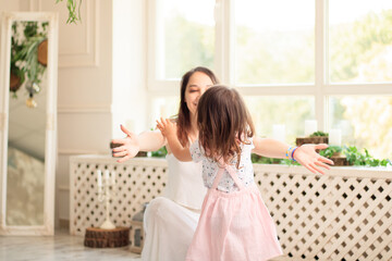 The child runs into the mother's arms to hug her. Family have fun in the house. The girl is happy to meet her mother. background image. Copy space